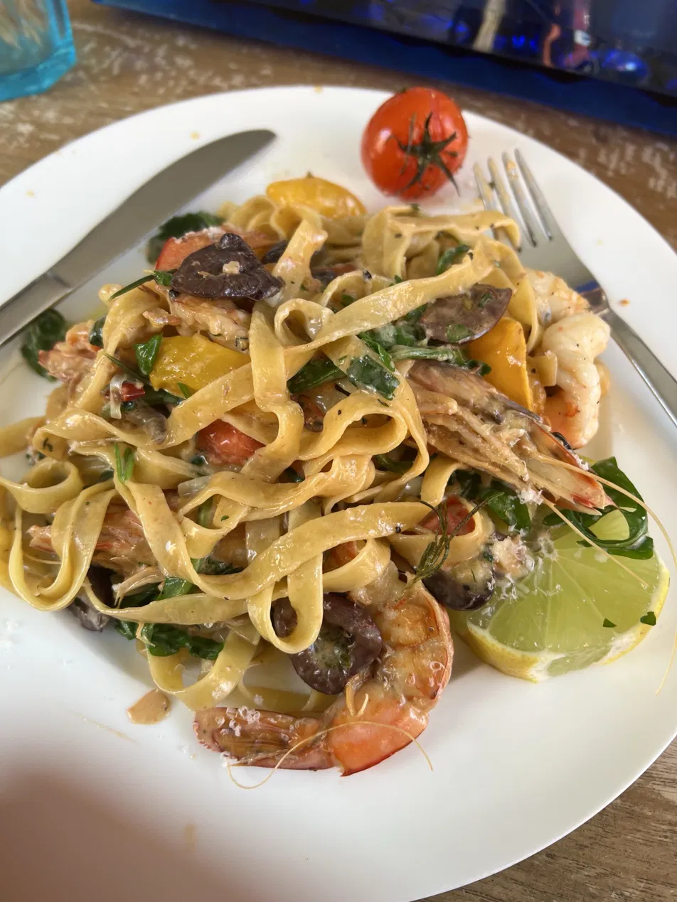 Fettuccine with prawns, olives, capsicum and rocket, served with a lime wedge